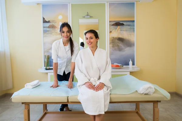 Woman beautician doctor with patient in spa wellness center. Young female professional cosmetologist make neck massage to beautiful brunette girl in cosmetology cabinet or beauty parlor.