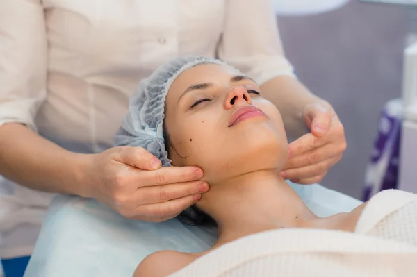 Beautiful young woman relaxing with face massage at beauty spa