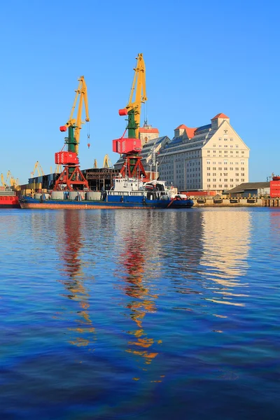 The ships and portal cranes are reflected in the Pregolya River