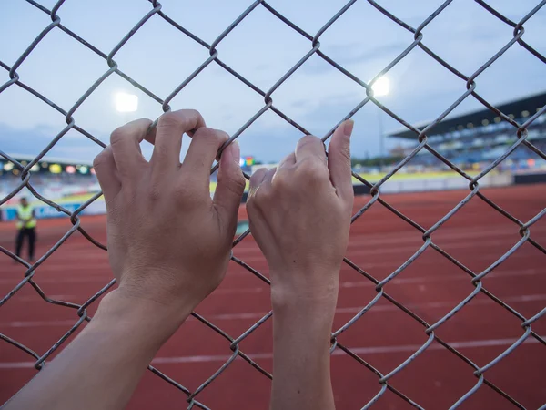 Close up on a woman\'s hands and  man\'s hands as They are holding on to a fence.