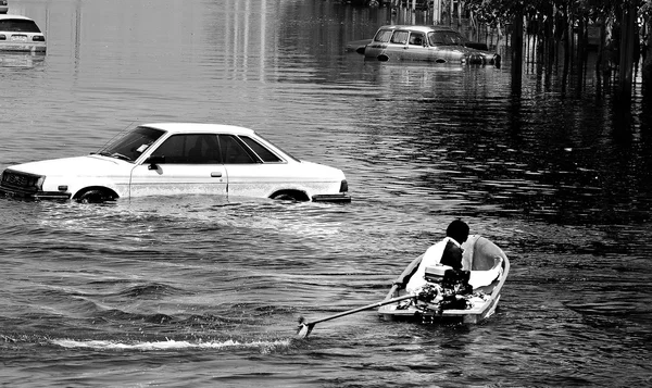 Man in boat and cars in water during flood