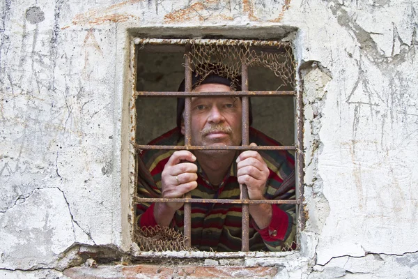 Man sitting behind prison grid