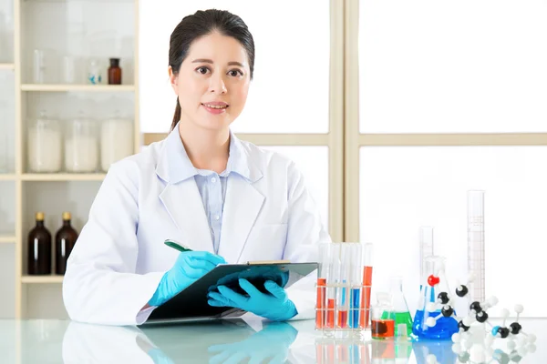 Smile female scientist recording her research data on clipboard