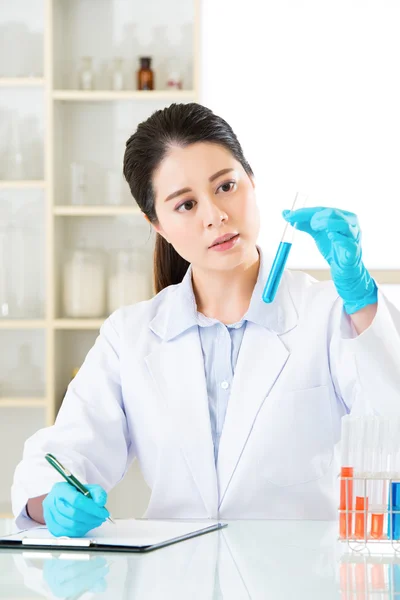 Asian female scientist recording her research data on clipboard