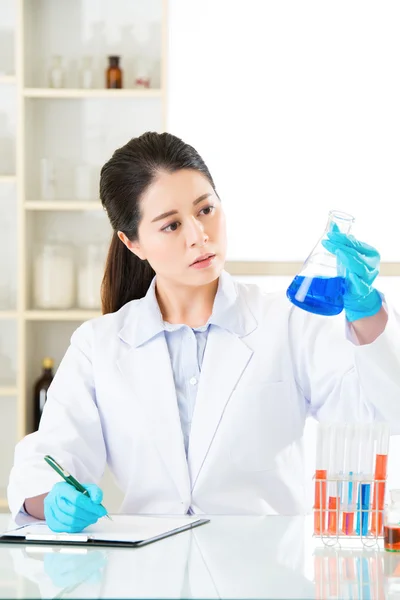 Asian female scientist recording her research data on clipboard