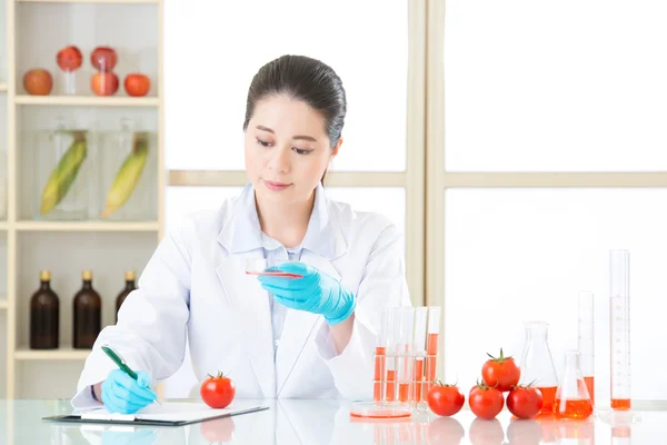 Asian female scientist thinking and holding an tomato