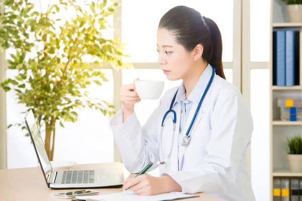 Doctor recording patient\'s condition on clipboard from computer,