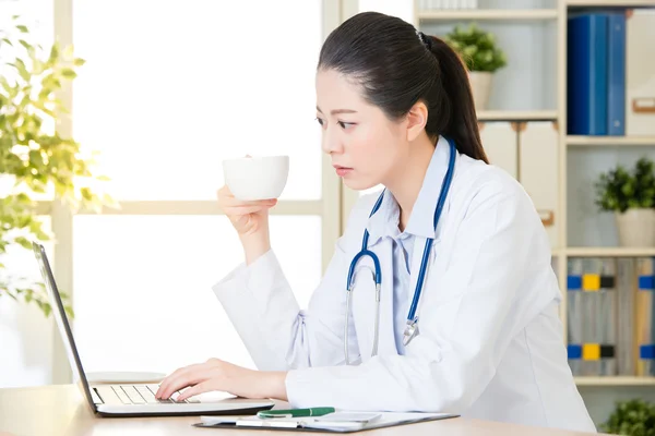 Doctor drinking coffee and using computer, healthcare and medici