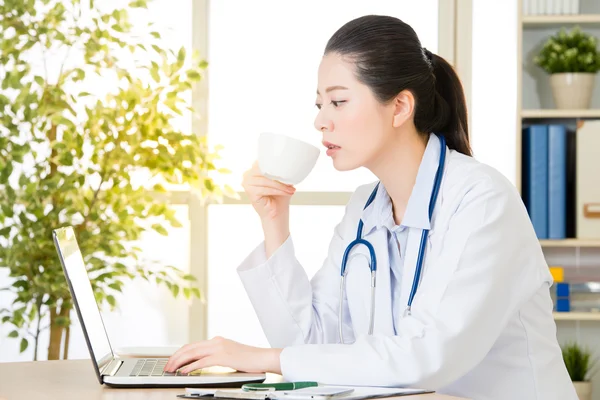 Doctor drinking coffee and using computer, healthcare and medici