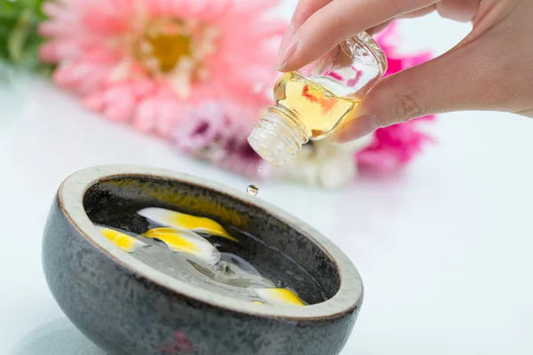 Essential oil dripping into petal water, with hand holding the g