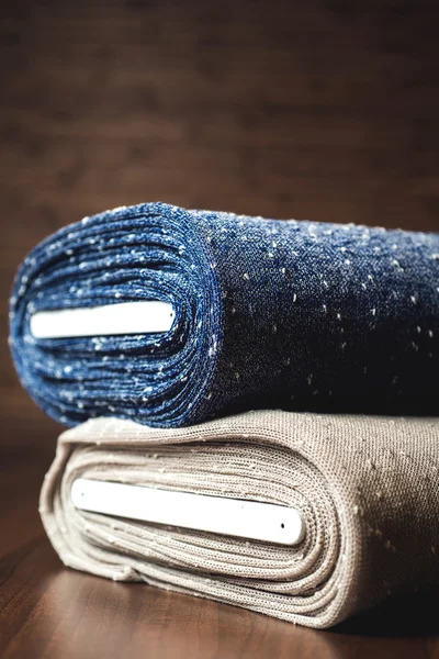 Rolls of blue and brown fabric on wooden background