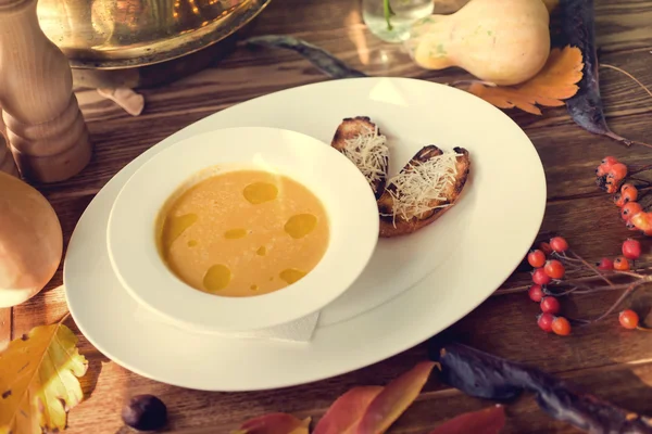 Bowl of pumpkin soup with bread crouton on wood table. Autumn decoration concept