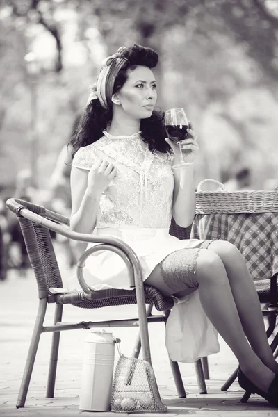 Beautiful young girl with glass of red wine alone in a street cafe