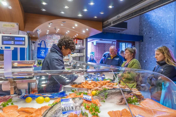 Shop assistant serving customers in a seafood shop in Melbourne