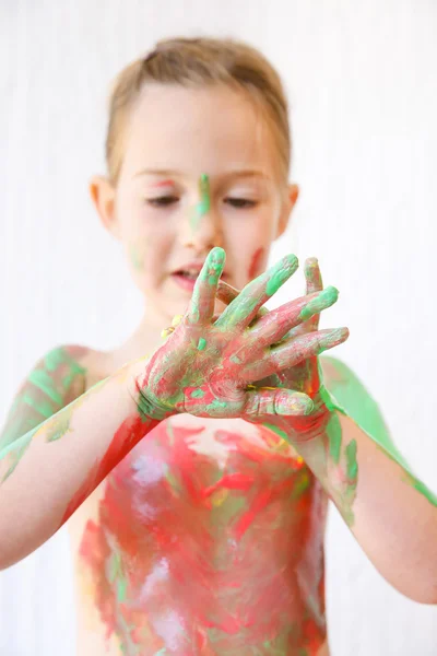 Little girl with hands hands covered in finger paint