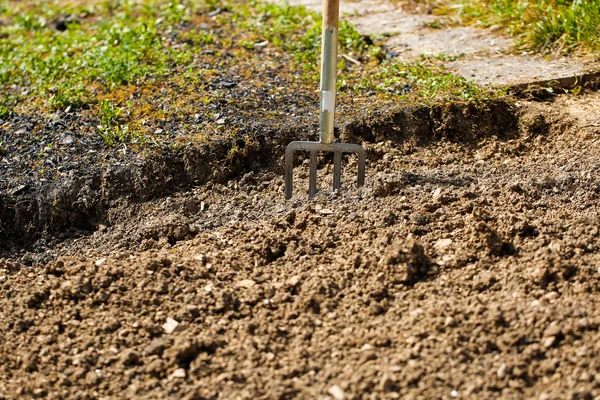 Garden fork pitched in soil, symbolizing garden work