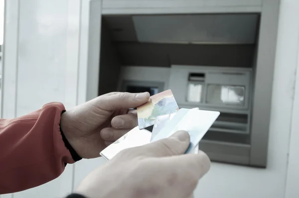 Man at ATM machine with stash of credit and debit cards