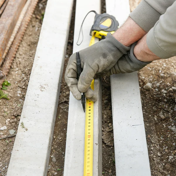 Construction worker measuring concrete pillar