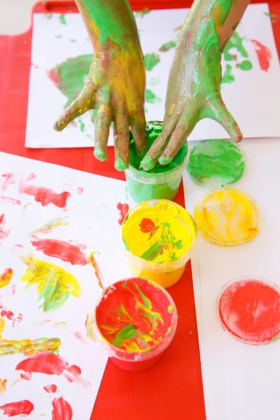 Child dipping fingers in non-toxic finger paints