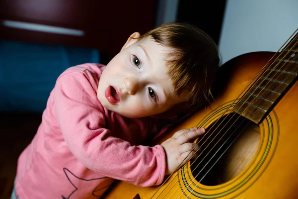 Small toddler listening to sound of a guitar