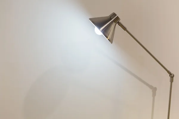 Turned on folding reading lamp against white wall