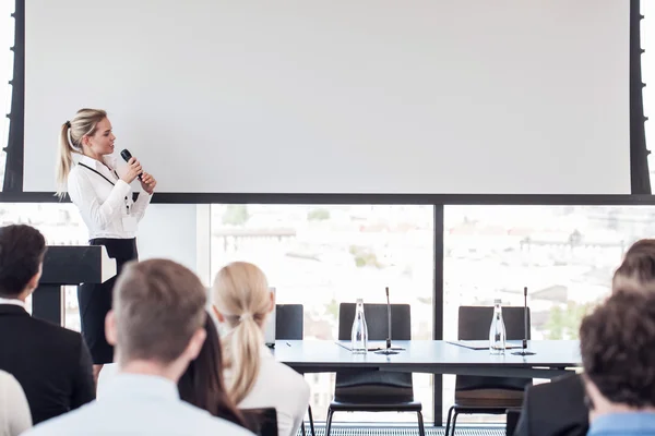 Business woman speaking at presentation in microphone in office