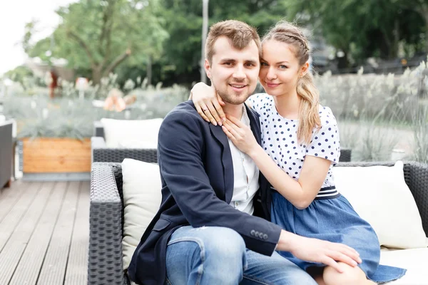 A young couple spends time on the couch in the outdoor cafe