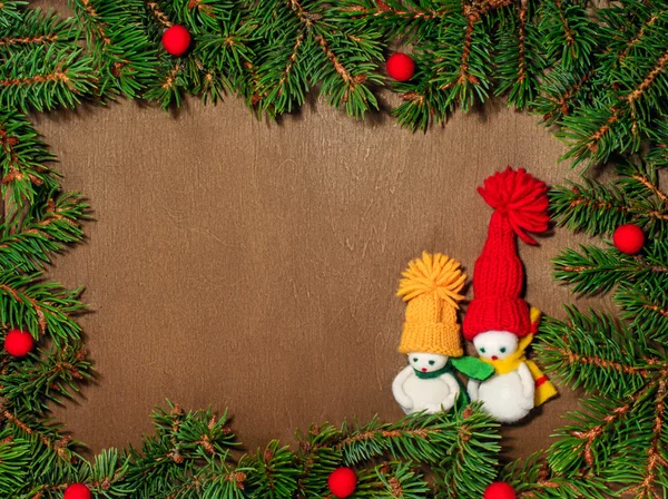 Two snowmans and christmas tree with red beads on the wooden background with  place for the text