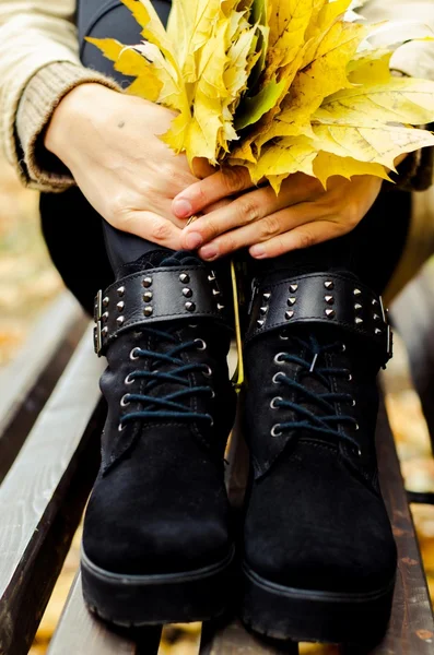 Leaves in female hands and feet in suede boots