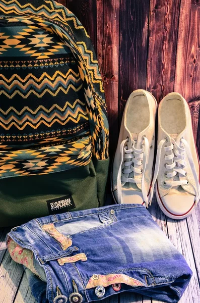 Blue jeans, white sneakers, green backpack