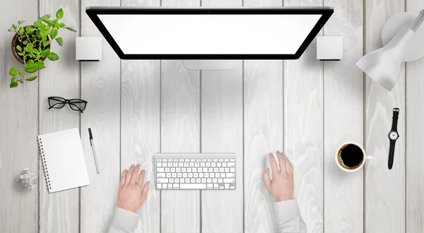 Modern desk with isolated computer display top view. Designer works with a mouse and keyboard. Coffee, lamp, paper, glasses, plant, watch on table.