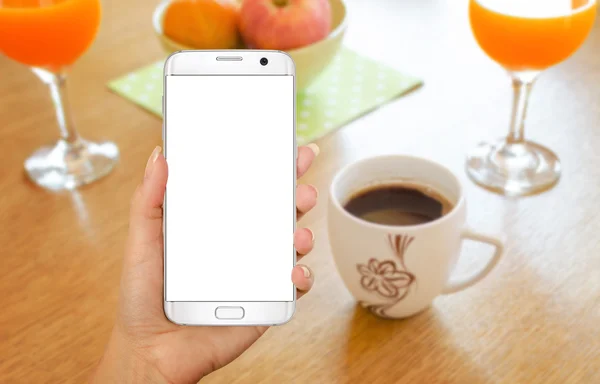 Smart phone with isolated display for mockup in hand. Relax time with coffee on table.