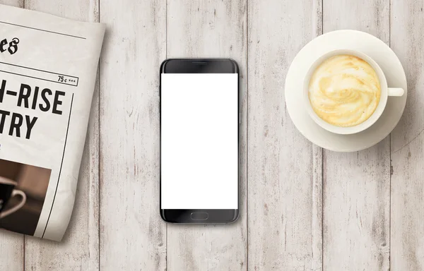 Smart phone with isolated display for mockup on table. Newspaper and coffee on table. Top view.