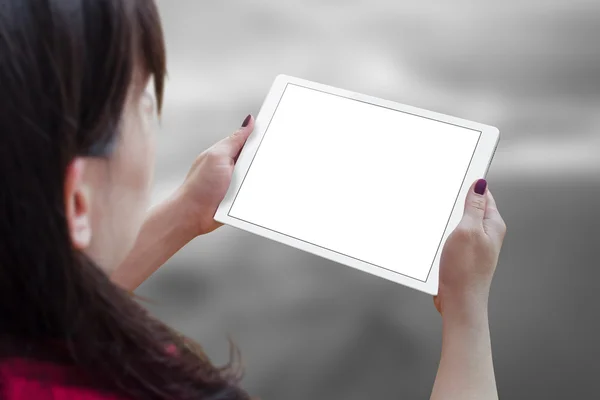 White tablet with blank, white, isolated screen for mockup in woman hand. City life in background