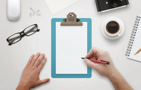 Man hand writing on notebook surrounded with office accessories