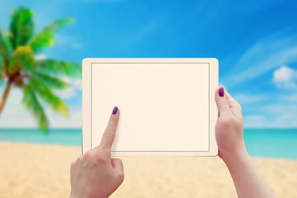 Woman work on tablet with blank screen. Summer time, beach in background.