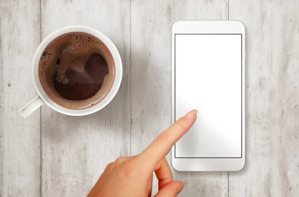 Woman touch smart phone with isolated white screen for mockup. Top view scene with coffee.