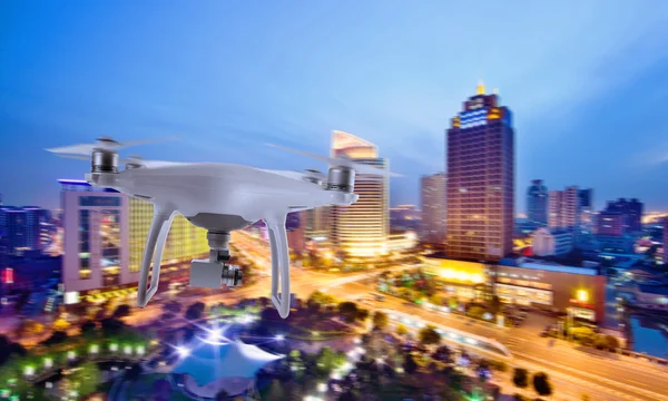 Drone quad copter with camera flying over the city center in night.