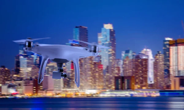 Drone quad copter with camera flying towards the city center in night.