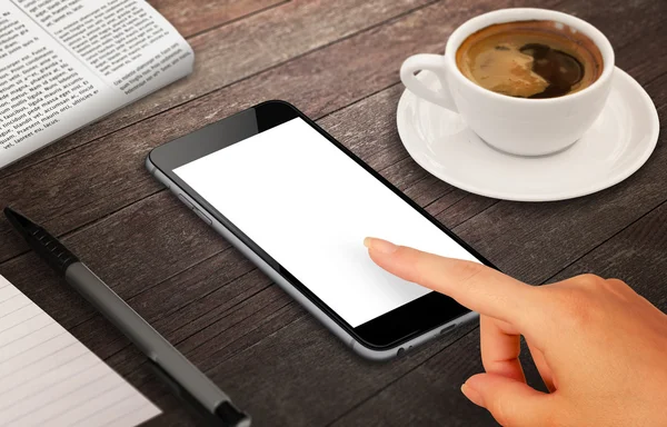 Woman touch smart phone with isolated white screen for mockup. Isometric view phone on table with coffee, pen, paper.
