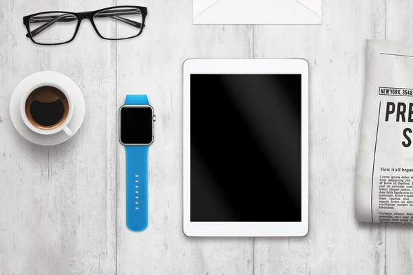 Smartwatch and tablet with isolated, blank screen for mockup. Top view scene. Coffee, newspaper, glasses on table.