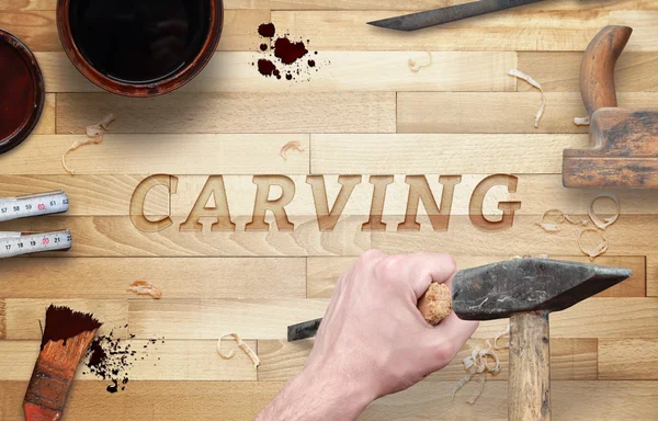 Carving word carved in wood with hammer and chisel. Beside is brush, paint, wood plane, ruler, shavings.