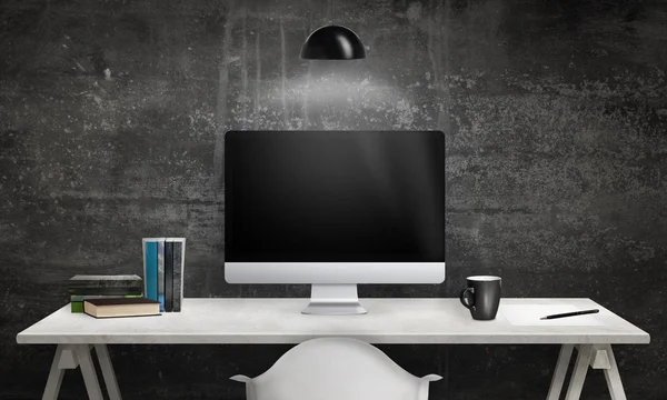 Computer display and books on office desk. Blank screen for mockup. Dark, black wall in background. Hanging lamp on top.