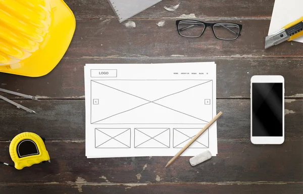Designer work on website idea. Work desk with smart phone, glasses, paper, pencil, construction tools.