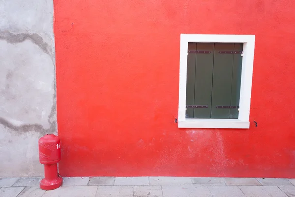 Detail of a red wall with hydrant from Burano island, Venice