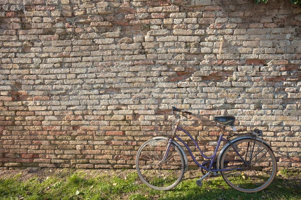 Old bicycle parked long an external wall in Burano island, Venic