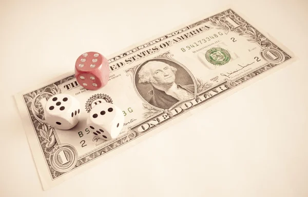 Gambling: two white dice and a red dice over a US one dollar bill