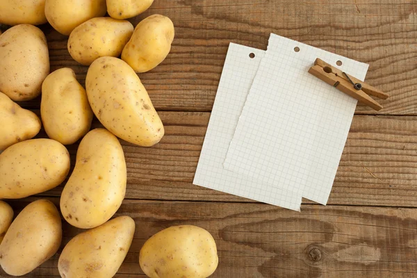 Block note on wooden table next to fresh potatoes