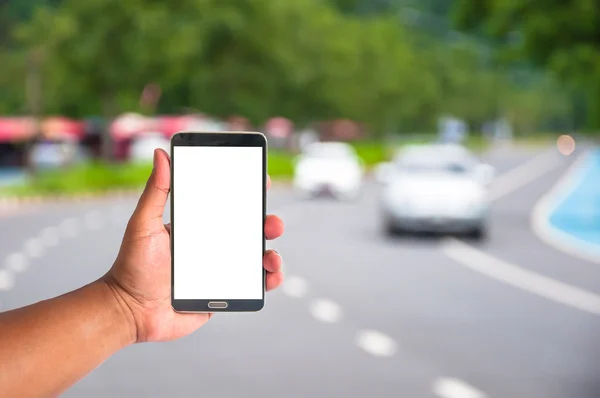 The hand of man hold mobile phone over blurred car on the road