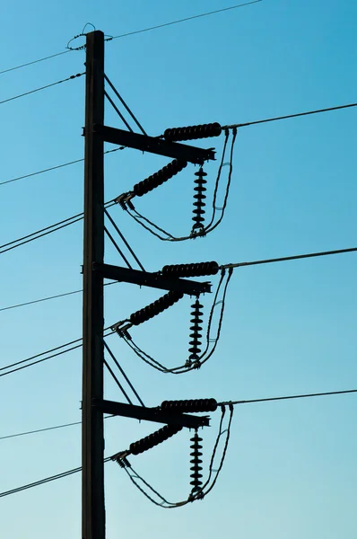 Silhouette of Electricity post in dark blue sky background